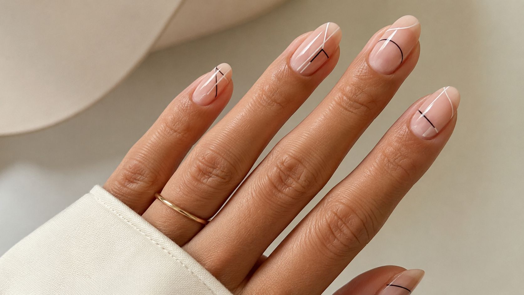 Elegancki i minimalistyczny manicure z delikatnymi geometrycznymi liniami na naturalnej płytce paznokcia w kolorze nude.